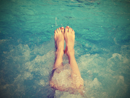 feet of young woman during the whirlpool therapy in the pool with old toned effect