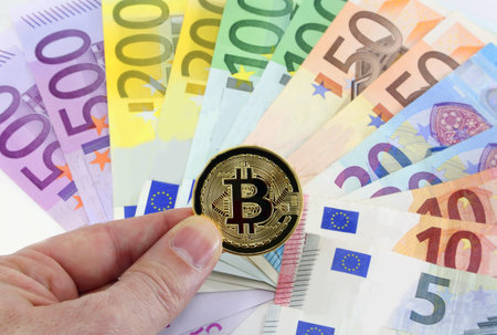 many money euros and a golden bitcoin on the hand