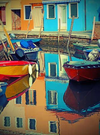 reflection in the water of canal of house and boats in BURANO near Venice in Italyの写真素材