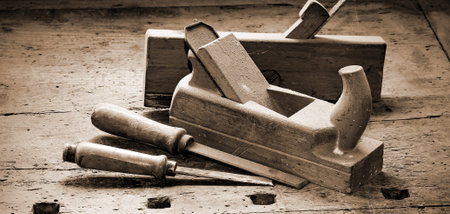two old planes and two chisels over the work table with the old wooden vise used in the carpenter's...