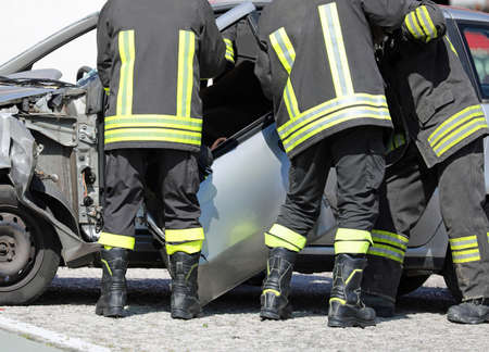 firemen remove the door of a destroyed car after a serious car accident to recover the injured motoristの写真素材