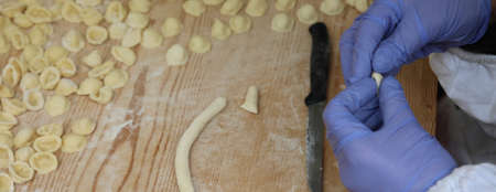 woman chef with blue gloves during the preparation of fresh italian pasta called Orecchiette a typical dish of Apulia Regionの写真素材