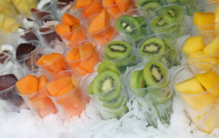 many glasses on ice with fruits such as melon kiwi pineapple and more