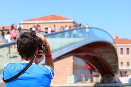 Boy photographs the modern bridge called Ponte della Costituzione that means Constitution Bridge in...