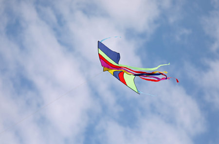 colorful kite flies high in the blue sky