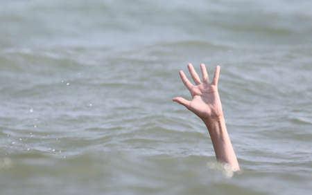 drowning bather holds up his hand for helpの写真素材