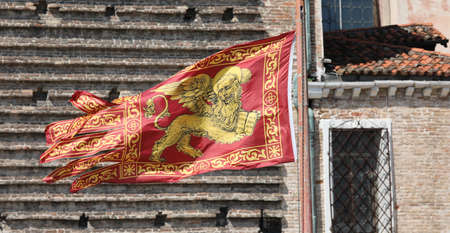 Golden Winged Lion on the Red Flag is the symbol of Serenissima in Venice in Italyの写真素材