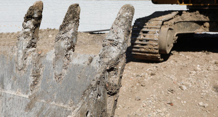 detail of a bucket of a bulldozer and the excavator in the background of a construction site