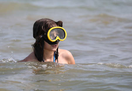 pretty caucasian little girl with diving mask on the oceanの写真素材
