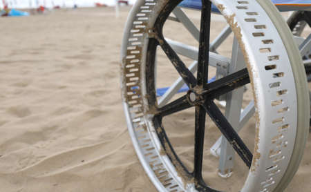 detail of the wheel of a special wheelchair to move easily in the sand of the sandy beach by the seaの写真素材