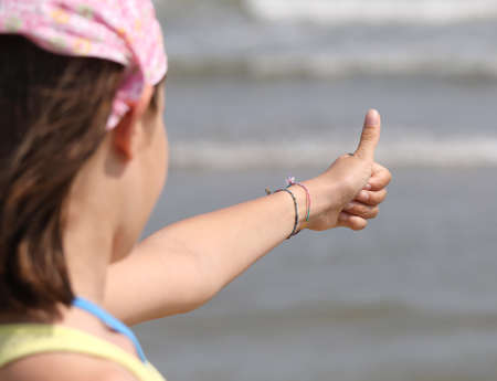 little girl and her thumbs up by the oceanの写真素材