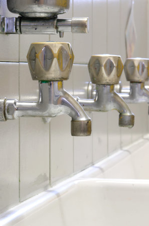 row taps in the school sink without children and the soap dispenser