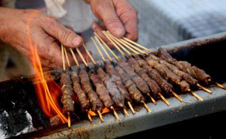 hands of cook while cooking mutton skewers called ARROSTICINI in the language of southern Italy