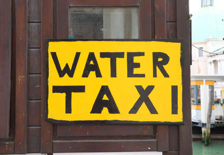 Large Yekllow sign with the inscription WATER TAXI to transport by ship in the navigable canals of Venice in Italyの写真素材
