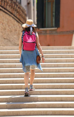 Young woman walking on the staircase with straw hatの写真素材