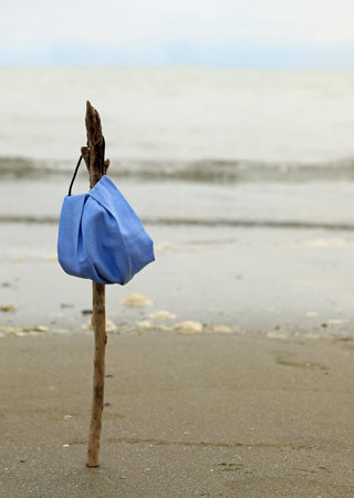 surgical mask on a twig by the sea symbol of hope and the end of the infections by Corona Virus