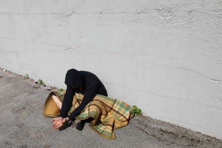 homeless man begging on the street under an old blanket and nobody sees himの写真素材