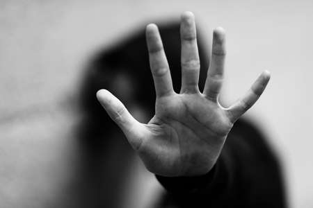 hand of the little girl who wants to protect herself from her attacker during an abuse with black and white effectの写真素材