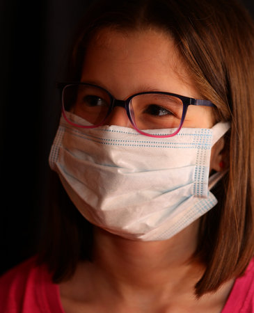 young girl with glasses wears the surgical mask to protect herself from the coronavirus epidemic