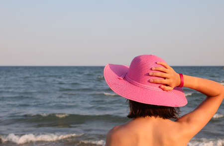 young girl in purple hat by the ocean waiting for the boatの写真素材