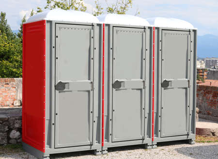 three portable toilets booths installed in a public park in the city and a large cabins for the disabledの写真素材