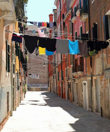narrow street of the European city with clothes hanging out to dry in the sun without people in summerの写真素材