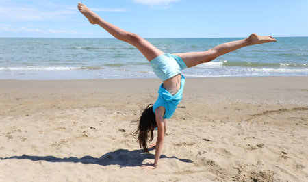 girl does gymnastics on the beach with a pirouette and legs in the air