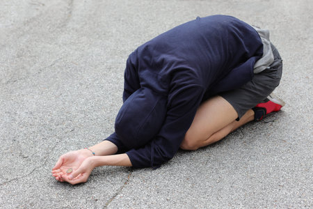 young gypsy crouched on the ground asks for alms to eat