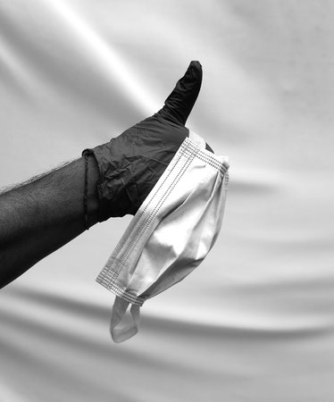 hand with surgical glove with thumb raised as a sign of success and perfection and surgical maskの写真素材