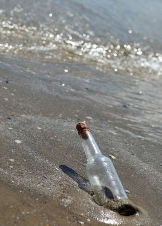 bottle stranded on the shore near the beach that can contain a secret message or a treasure mapの写真素材