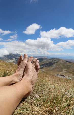 barefoot feet of caucasian man hiker walker after hiking in high mountains during restful rest stopの写真素材