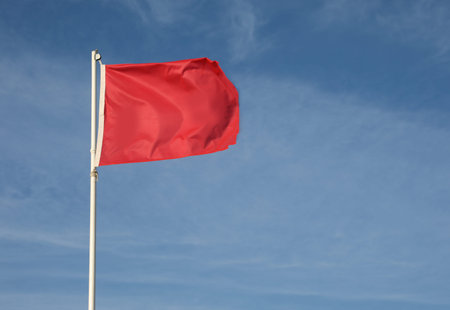 big red flag on the blue sky symbol of danger and hazard