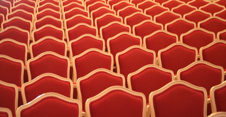 empty elegant red velvet chairs of an indoor theater without peopleの写真素材
