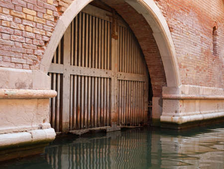 wooden gate of the main door that directly accesses the navigable canal in Venice used as a garage for boats by the Venetiansの写真素材