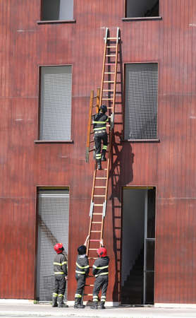 fire brigade team performing an exercise in using the stairs to reach the upper floors of the house and enter through the windowsの写真素材