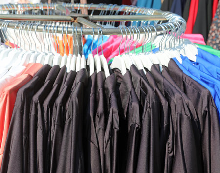 black clothes and aprons for kindergarten and elementary school hanging on the coat rack in a trendy...