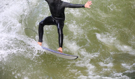 young athlete does surf balancing on the surfboard on the river in the city of munich in Germany