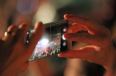 woman takes a movie with smartphone during live concert with many spectatorsの写真素材