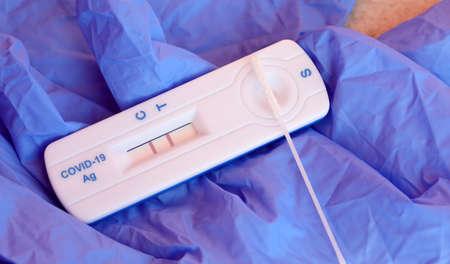 rapid test to diagnose coronavirus positivity with nasal swab and the result with two lines sign of infection in progressの写真素材