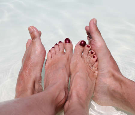 Four feet of a couple of lovers relaxes in the middle of the pool during their honeymoon in the resortの写真素材