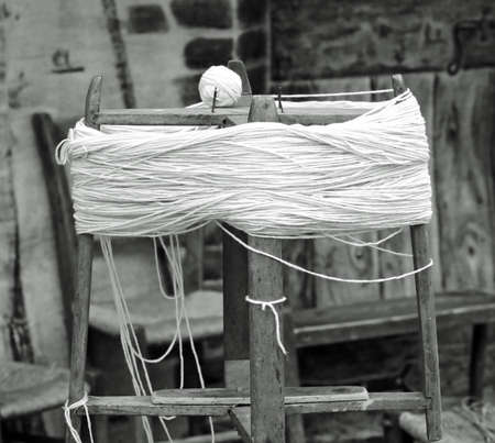 antique wooden spinning wheel or swift with the skein of wool below and the ball of yarn above with an antique effect in black and whiteの写真素材