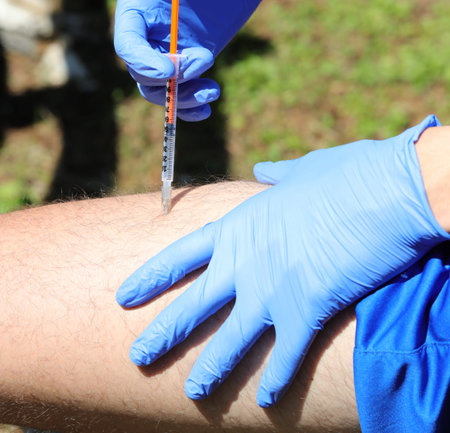 boy with blue latex gloves while injecting insulin dose on his thigh because he has diabetes