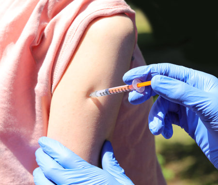 during vaccination of young female student with syringe with mRna vaccine and arm without seeing...