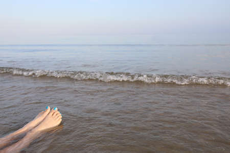 two legs of woman with feet with nail polish while relaxing by the sea in summerの写真素材