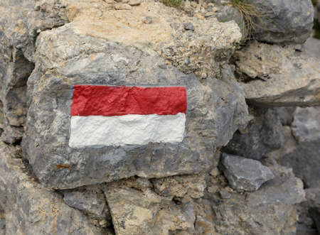 red and white stripes to mark the trail in the mountains on a rockの写真素材