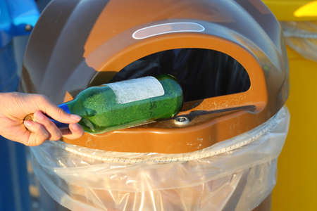 hand of little girl while throwing away a glass bottle in the recycling binの写真素材