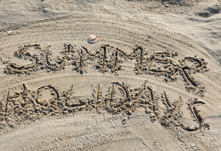 text with the words SUMMER HOLIDAYS in capital letters on the sand of the sandy beachの写真素材