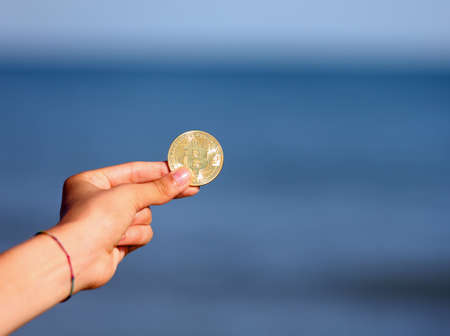 hand holding a golden coins with the large letter B symbolizing the bitcoin cryptocurrencyの写真素材