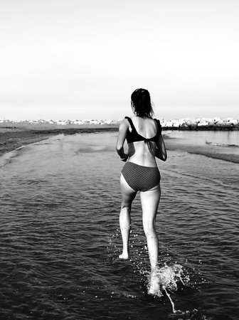 girl running on sea water in summer during sports training with black and white effectの写真素材