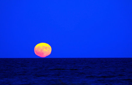 big red moon on fire with reflection on the sea in the eveningの写真素材